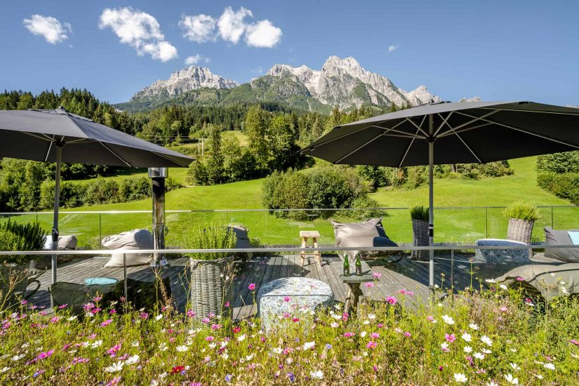 Dachterrasse im Sommer mit Blumen und Blick auf die Leoganger Steinberge