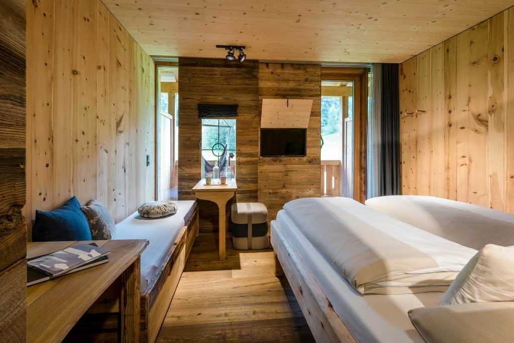 Bett und Sitzecke im stylischem Hotelzimmer mit viel Holz