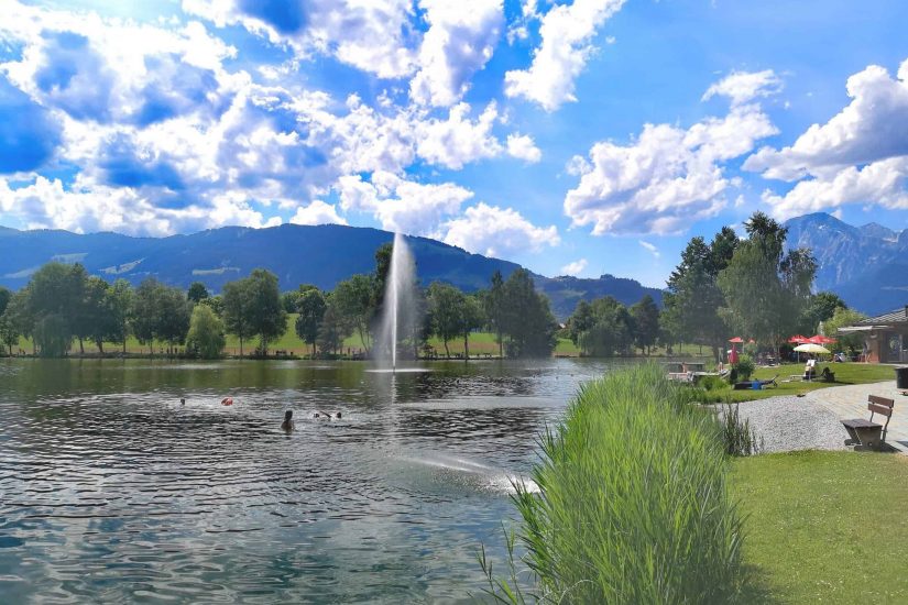 See Badesee Strandbad mit Fontäne Wasserspiel Berge Schwimmbad Saalfelden umsonst