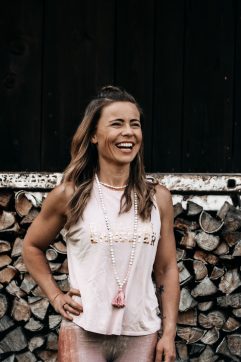 Lisa Stampfer lachend vor Baumstämmen